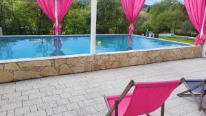 a pink chair sitting in front of a swimming pool at Lawendowy dworek in Paszowa +5 photos