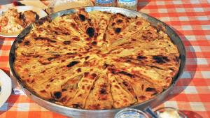 a pizza in a pan on a table at Guest House Tofaj in Deçan +14 photos