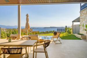 a patio with a table and chairs and a view of the ocean at Thea Suites in Ouranoupoli