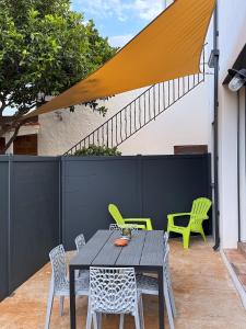 un patio con tavolo, sedie e una recinzione di Hébergement de Standing à la Mer avec extérieur a Banyuls-sur-Mer