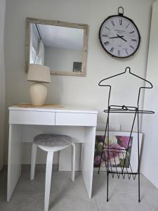 a white desk with a mirror and a clock on the wall at Apartman Ivy in Premantura