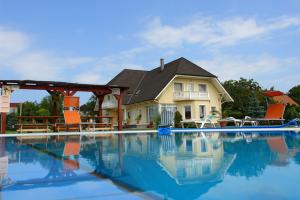 a house with a swimming pool in front of a house at Ilona Apartmanházak in Gyenesdiás