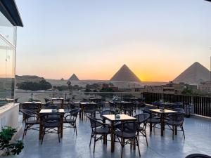 a view of the pyramids from a restaurant with tables and chairs at AKHNATON Pyramids View Hotel With Rooftop Access & free airport pickup in Cairo +266 photos