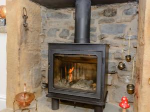 a stone fireplace with a fire in it at Whibberley Cottage in Ashford
