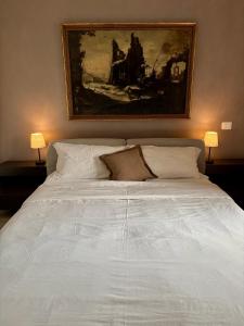 a bedroom with a white bed with a painting on the wall at Ales apartment in Cuneo