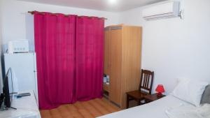 a bedroom with pink curtains and a bed and a desk at Studio privé climatisé en bas de villa in Fort-de-France