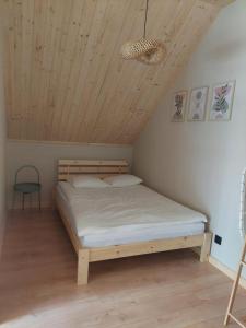 a bed in a room with a wooden ceiling at Dominickie Antresole in Boszkowo-Letnisko