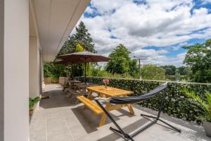 a patio with a wooden table and chairs and an umbrella at Appart 10personnes Terrasse vue Loire, Parkings Voitures Vélos,10min Centre Blois,40min Zoo Beauval in Blois