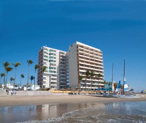 twee hoge gebouwen op een strand met palmbomen bij Las Flores Beach Resort in Mazatlán