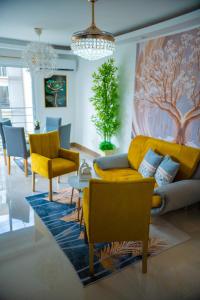 a living room with a yellow couch and chairs at Ronya A406 in Punta Cana