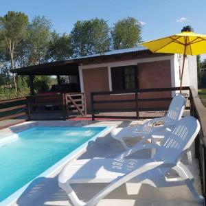 un paio di sedie e un ombrellone accanto a una piscina di Cabañas Los Abuelos a Santa Rosa de Calamuchita