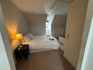 Un dormitorio pequeño con una cama blanca y una lámpara. en Cornflower Cottage, 