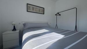 a white bedroom with a bed and a lamp at A Casiña do Castiñeiro, Melide in Melide