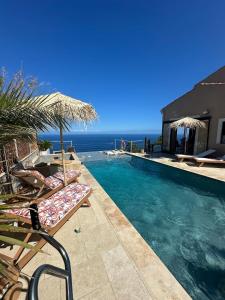 a swimming pool with two lounge chairs and the ocean at Villa Naïma Esterel in Saint-Raphaël