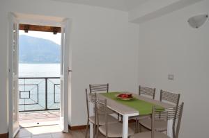 a dining room with a table and chairs and a balcony at Lierna Beach Apartments in Lierna