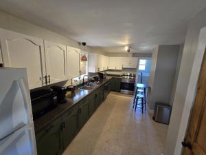 a large kitchen with white cabinets and a table at The Stirton House in Shelburne
