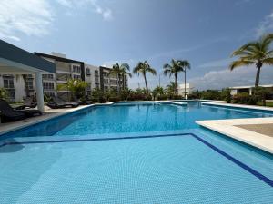 a large blue swimming pool with palm trees and buildings at Puerta al Sol in Acapulco