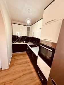 a kitchen with black and white appliances and wooden floors at Holiday Home Lezha 2 in Lezhë