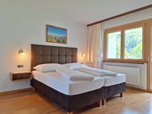 a bedroom with a large bed with a large window at Alpenzeit Zillertal Apartments in Zell am Ziller