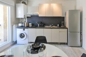 a kitchen with a table and a white refrigerator at Le Rétro - Hyper Centre - Balcon et terrasse in Tarbes