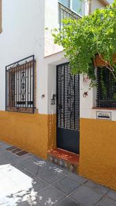 un bâtiment jaune et blanc avec une porte noire dans l'établissement Casa de la Portuguesa, bonita terraza con barbacoa, à Güéjar-Sierra