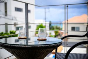 two wine glasses sitting on a table on a balcony at onna resort nakadomari ビーチまで車で4分 最大8名OK 中庭付き貸切ヴィラでくつろぐ恩納村ステイ in Onna