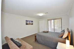 a bedroom with a bed and a couch and a window at Villa Palazzo 3 - Kalbarri, WA in Kalbarri