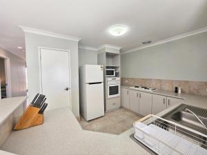 a kitchen with a white refrigerator and a sink at Pelican Shore Villa 22 - Kalbarri WA in Kalbarri
