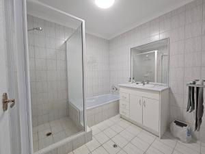 a bathroom with a shower and a sink and a tub at Pelican Shore Villa 22 - Kalbarri WA in Kalbarri +4 photos