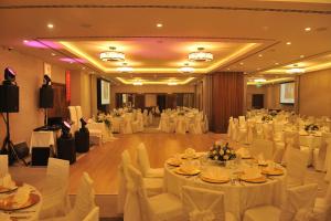 a banquet hall with white tables and white chairs at Ramada Hotel & Suites by Wyndham Adana in Adana