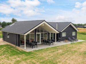 une grande maison noire avec une terrasse et un patio dans l'établissement 5 star holiday home in Idestrup, à Bøtø By