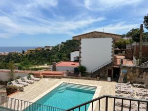 a swimming pool on top of a building with chairs at Sailor Apartment sea views in Tossa de Mar