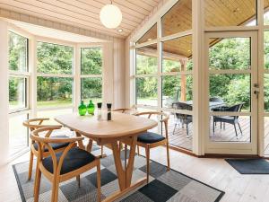 een eetkamer met een tafel, stoelen en ramen bij 6 person holiday home in Løgstør in Løgsted