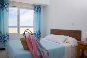 a bedroom with a bed with a view of the beach at Apartamentos Calypso in Punta Umbría