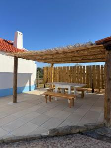 a picnic table under a wooden pergola on a patio at Monte da Carrasqueira in Santiago do Cacém