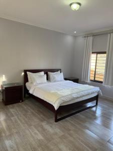 a bedroom with a bed with white sheets and pillows at MY Home Apartments in Lusaka