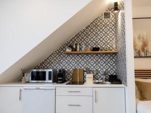 a kitchen with white cabinets and a tile wall at Alvor Serene House I in Alvor