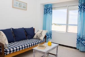 a living room with a couch and a window with the beach at Apartamentos Calypso in Punta Umbría