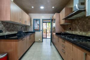 a large kitchen with wooden cabinets and black counter tops at CASA DE GOLF Oasis Artistique avec Piscine & Vue Golf, Proche Aéroport in Bouskoura