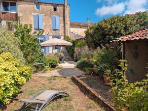 LusignanMaison Galice à Lusignan village médiéval - Base loisir gratuite- 30 min Futuroscope的一个带椅子和遮阳伞的花园