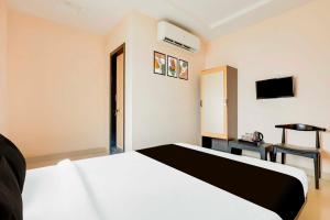 a hotel room with a white bed and a television at Townhouse Kakinada Town Junction in Kākināda