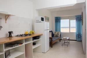 a kitchen with a white refrigerator and a table at Apartamentos Calypso in Punta Umbría