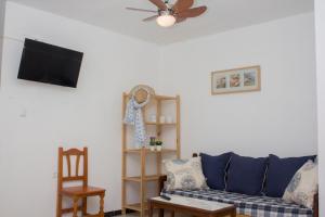 a living room with a blue couch and a ceiling fan at Apartamentos Calypso in Punta Umbría