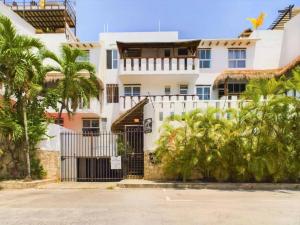 a white building with palm trees in front of it at Stylish 1BR Apartment with Private Terrace in Playa del Carmen in Playa del Carmen