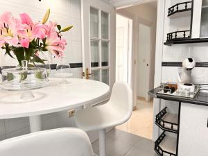 a white kitchen with a vase of pink flowers on a table at Apartment with private parking included - Granada in La Zubia +47 photos