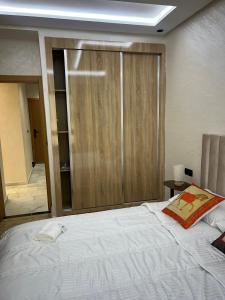 a bedroom with a large white bed and a closet at Very nice modern air-conditioned apartment in Fez in Fès