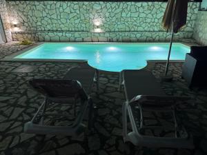 two chairs and an umbrella next to a swimming pool at AD Homes in Ravanj +7 photos