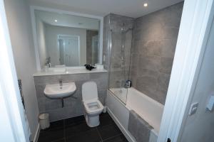 a bathroom with a sink and a toilet and a bath tub at Luxury 2 Bed Penthouse Manchester Large Balcony in Manchester +22 photos