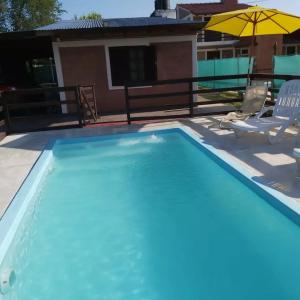 a swimming pool with a house in the background at Cabañas Los Abuelos in Santa Rosa de Calamuchita