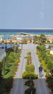 a man walking down a sidewalk near the beach at Scandic resort chalet sea view in Hurghada